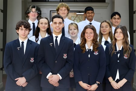 Un grupo de estudiantes de la Newcastle High School está frente a un edificio con arquitectura tradicional.