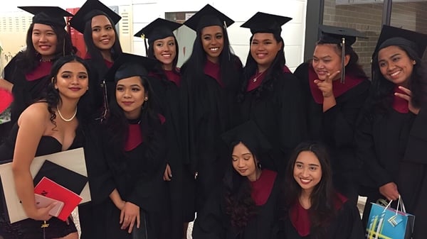 Un grupo de estudiantes sonrientes en ropa de graduación está frente al edificio de la Newtonbrook Secondary School.
