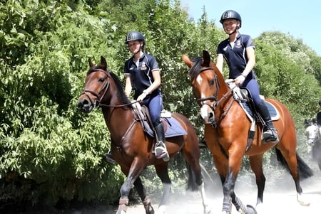 Dos personas en uniformes de policía montan a caballo a través de un entorno verde en el terreno de la Nga Tawa Diocesan School.