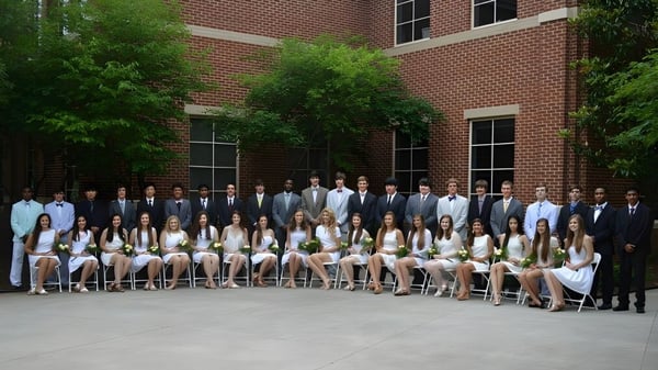 Un grupo de estudiantes está frente a un edificio de ladrillo en el campus de la North Cross School.