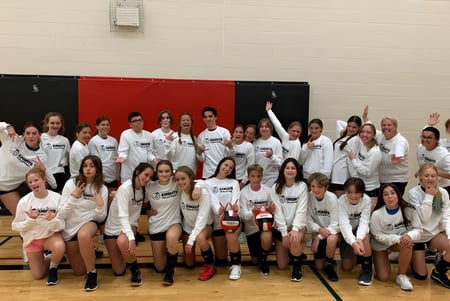 Un gran grupo de jóvenes estudiantes en uniformes deportivos se reúne en el gimnasio de la North Grenville District High School.