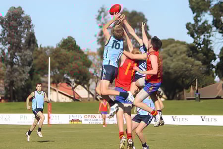Estudiantes de North Lakes State College compiten por el balón en una competencia deportiva en el campo.