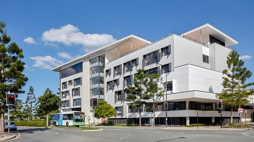 El moderno edificio de varios pisos de North Lakes State College con áreas residenciales y comerciales y vegetación circundante.