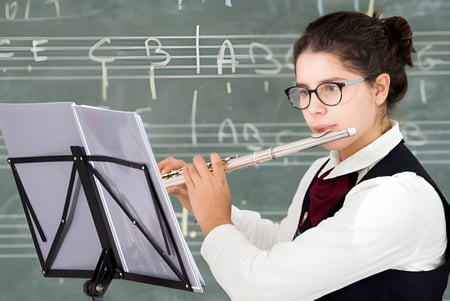 Una estudiante de la North London Grammar School toca la flauta frente a una pizarra.