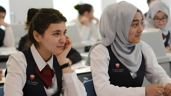 Dos alumnas de la North London Grammar School están sentadas en uniformes escolares en el aula en un escritorio.