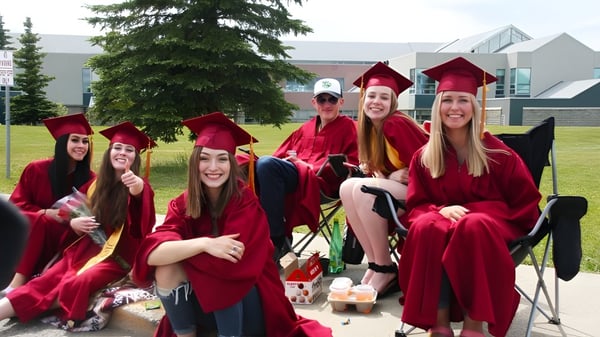 Un grupo de estudiantes de la North Peace Secondary School lleva togas rojas de graduación y posan en el campus para una foto.