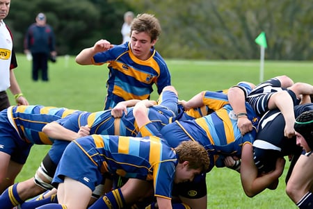Un grupo de jugadores de rugby del Northcote College lucha por el balón en un scrum en el campo.