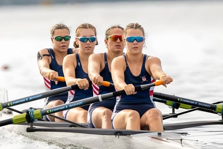 Cuatro estudiantes de Northfield Mount Hermon entrenan en el bote de remo sobre el agua.