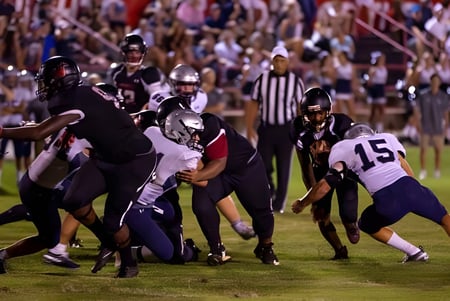 Estudiantes de la Northside Christian Academy juegan en el campo de fútbol frente a una gran multitud.