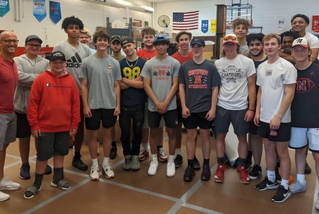 Un grupo de estudiantes está junto en un aula en el campus de la Northview High School con banderas de fondo.