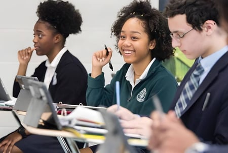 Estudiantes de Northwest Catholic High School trabajan juntos en un proyecto de aprendizaje con laptops en el aula.