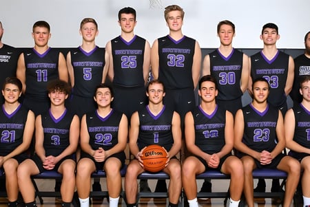 El equipo de baloncesto de la Northwest Christian High School posa junto en el gimnasio con uniformes morados y negros.