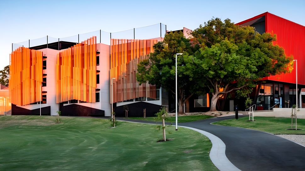 El moderno edificio de la Norwood International High School con fachadas rojas y naranjas en un paisaje verde.