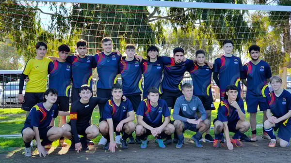 Un grupo de estudiantes de la Norwood International High School posan frente a una portería en el campus escolar.