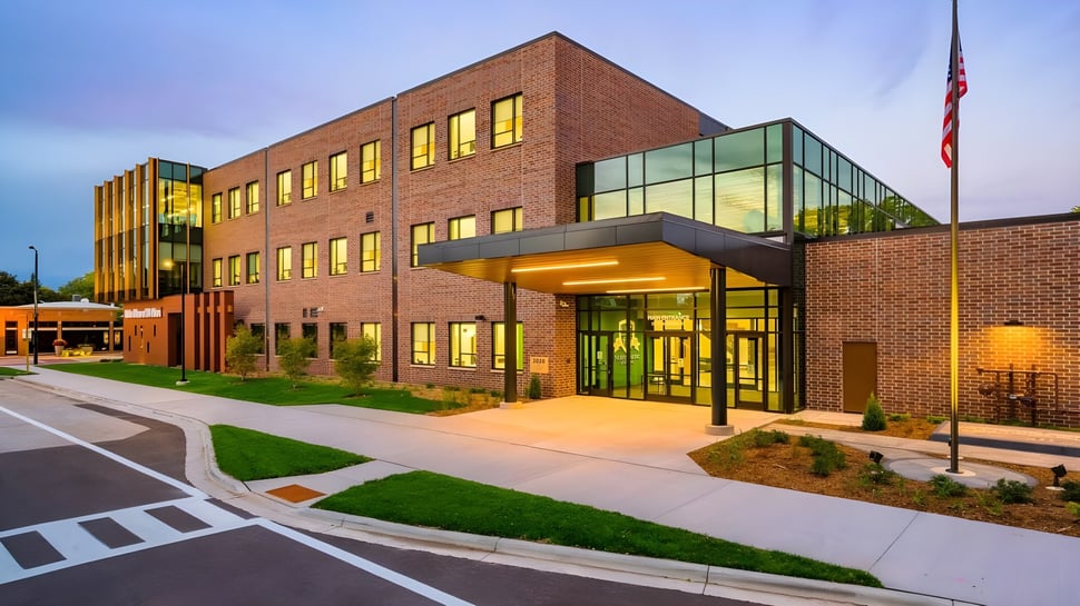 El moderno edificio de varios pisos de la Notre Dame de la Baie Academy, con grandes ventanales y una entrada acogedora, está rodeado de un cuidado espacio exterior.