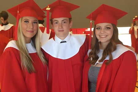 Tres estudiantes llevan ropa de graduación roja en el campus de la Nottawasaga Pines Secondary School.