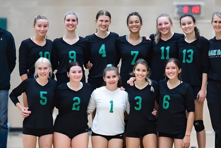 Un grupo de estudiantes de la Oak Bay Secondary High School posa junto a su entrenador al fondo.