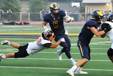 Estudiantes de la Oakridge Secondary School juegan al fútbol americano durante un intenso partido en el campo.