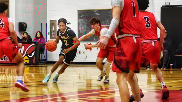 Estudiantes de la Oakville Trafalgar High School juegan un partido de baloncesto en un suelo de madera frente a espectadores.