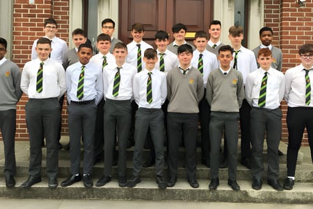 Un grupo de alumnos está en la escalera de un edificio de ladrillo en el campus del Oatlands College.