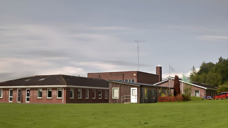 El edificio del O’Carolan College está en un prado y está rodeado de árboles.