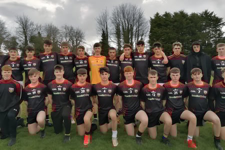 Un grupo de estudiantes del O’Carolan College posan juntos en un campo de fútbol con árboles al fondo.