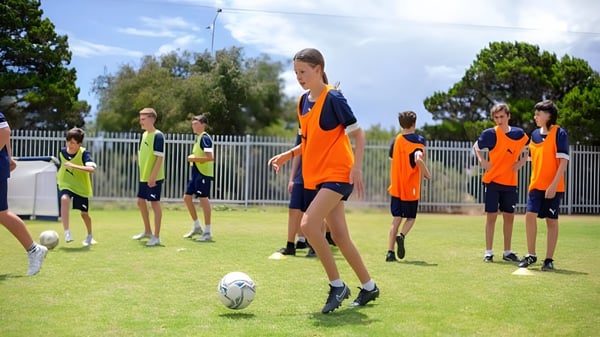 Un grupo de estudiantes de la Ocean Reef Senior High School está en camiseta de fútbol en un campo con árboles de fondo.