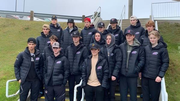 Un grupo de estudiantes de la O'Donel High School está con chaquetas y gorras negras frente a un estadio.