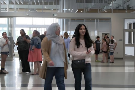 Un grupo de estudiantes está en el luminoso pasillo de la Ohpaho Secondary School con grandes ventanas.