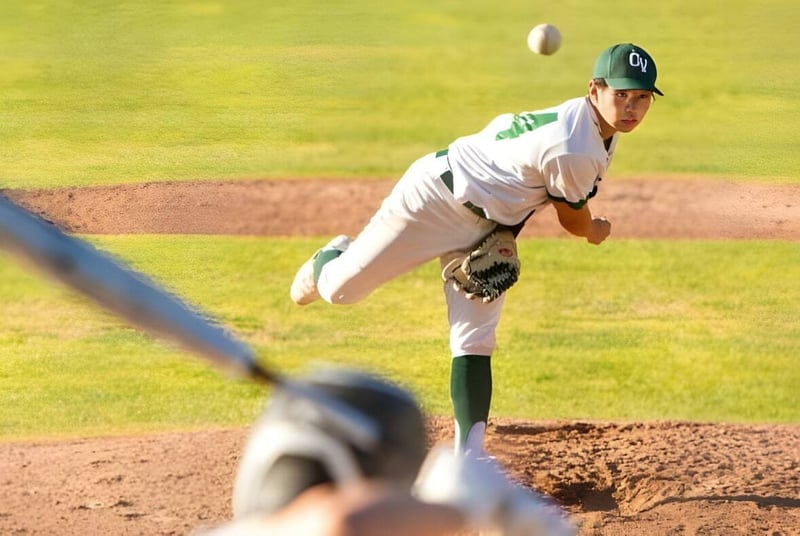 Un lanzador de béisbol con uniforme verde y blanco está en la colina de la Ojai Valley School y se prepara para un lanzamiento.