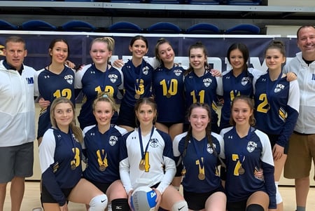 Un grupo de jóvenes deportistas de la Okanagan Mission Secondary School posan juntos en un gimnasio.