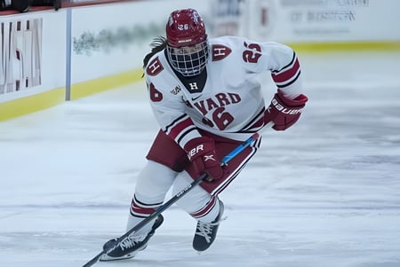 Un jugador de hockey de la Ontario Hockey Academy con uniforme blanco corre en la pista de hielo en la arena deportiva.