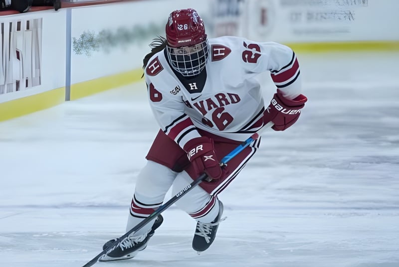 Un jugador de hockey de la Ontario Hockey Academy con uniforme blanco corre en la pista de hielo en la arena deportiva.