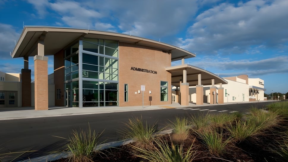 Un edificio moderno con fachada de vidrio y techo curvado en el terreno de las Orange County Public Schools.