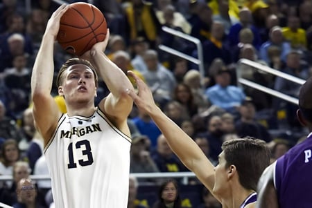 Un jugador de baloncesto de la Orangeville District Secondary School salta hacia la canasta mientras se pueden ver espectadores al fondo.