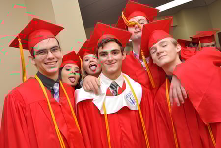 Un grupo de graduados de la Orangewood Christian School posan con togas rojas juntos frente a un fondo sencillo.