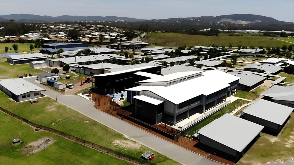 Vista del barrio residencial montañoso cerca de la Ormeau Woods State High School con casas modernas y tradicionales en medio de áreas verdes.