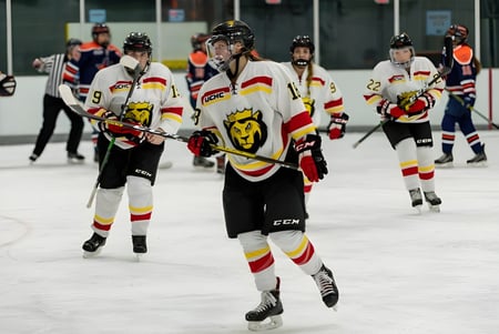 Estudiantes de la Osgoode Township High School juegan un partido de hockey en la pista de hielo frente a espectadores.
