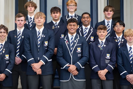 Un grupo de estudiantes está frente al edificio de la Otago Boys' High School con grandes ventanas.