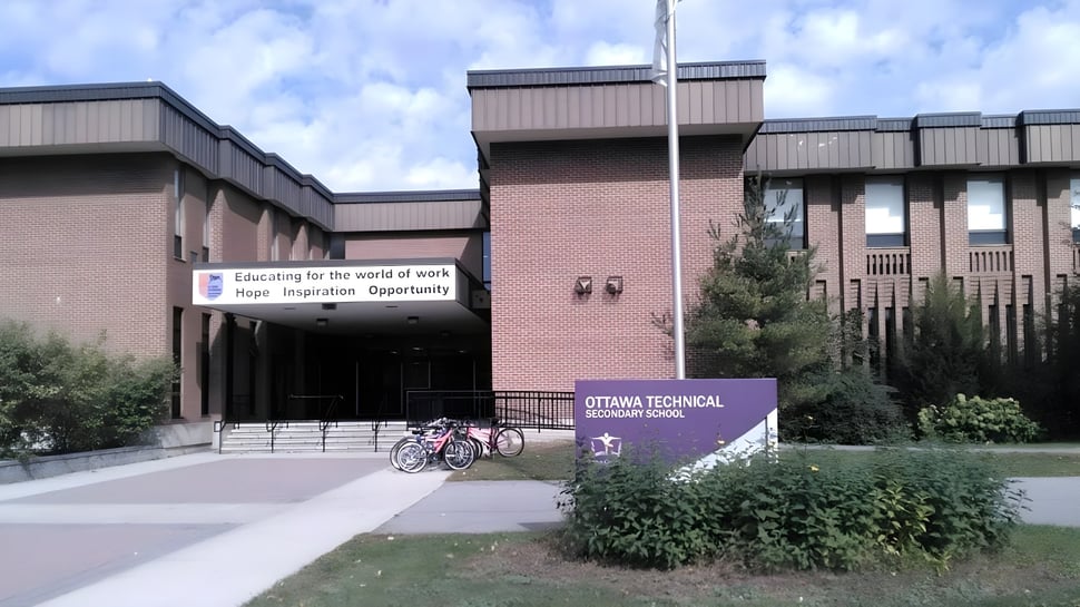 El moderno edificio de ladrillo de la Ottawa Technical Secondary School con bicicletas frente a la entrada bajo un cielo nublado.