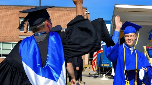 Graduadas y graduados de la Ottawa Technical Secondary School celebran su graduación frente a un edificio de ladrillo.