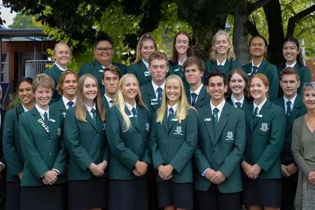 Un grupo de estudiantes del Otumoetai College está al aire libre con árboles y edificios de fondo.