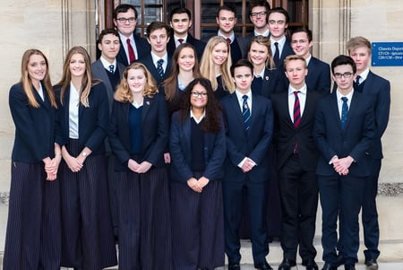 Un grupo de estudiantes en ropa formal está frente a un edificio de Oundle School.