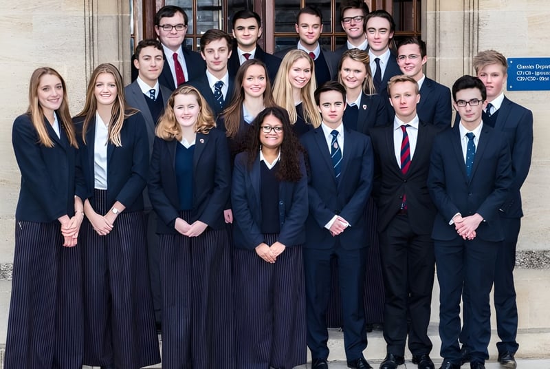 Un grupo de estudiantes en ropa formal está frente a un edificio de Oundle School.