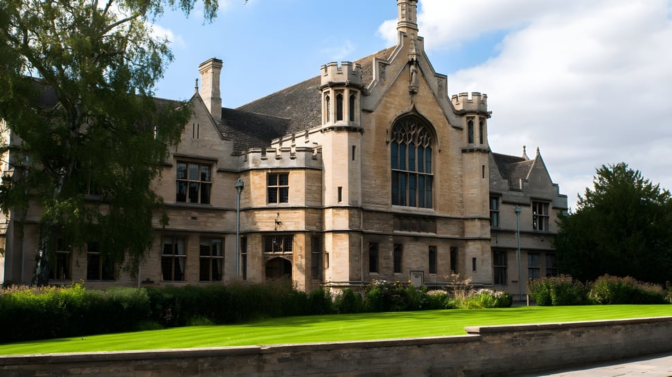 La mansión medieval en el terreno de Oundle School está rodeada de un césped verde y árboles.