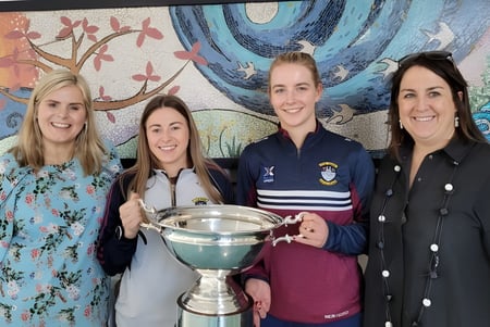 Cuatro estudiantes de la Our Lady´s Bower Secondary School sostienen juntas un trofeo frente a un colorido mural.