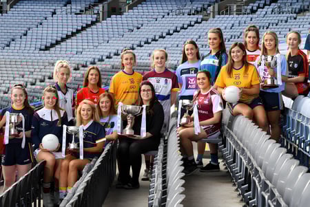 Un grupo de jugadoras de fútbol posan juntas en las gradas del estadio de Our Lady's College.