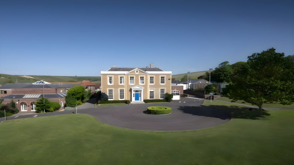 El destacado edificio amarillo del Oxford International College Brighton con una entrada redonda y céspedes bien cuidados.