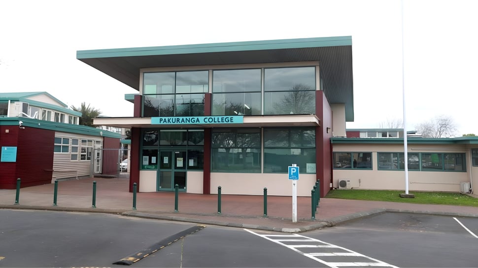 El moderno edificio de varios pisos con grandes ventanas en el campus del Pakuranga College con un estacionamiento en primer plano.
