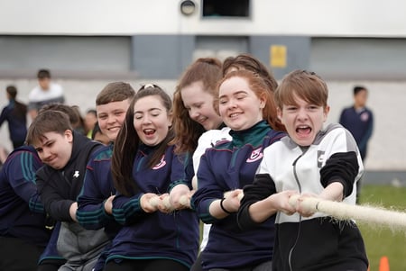 Estudiantes de la Palmerstown Community School celebran juntos en un campo de deportes frente a un edificio escolar.